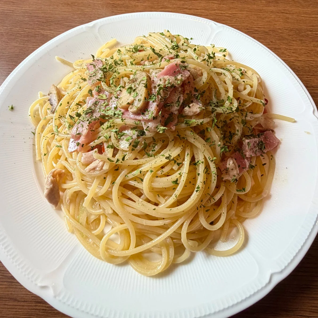白い皿に盛られたベーコンとキノコのパスタ