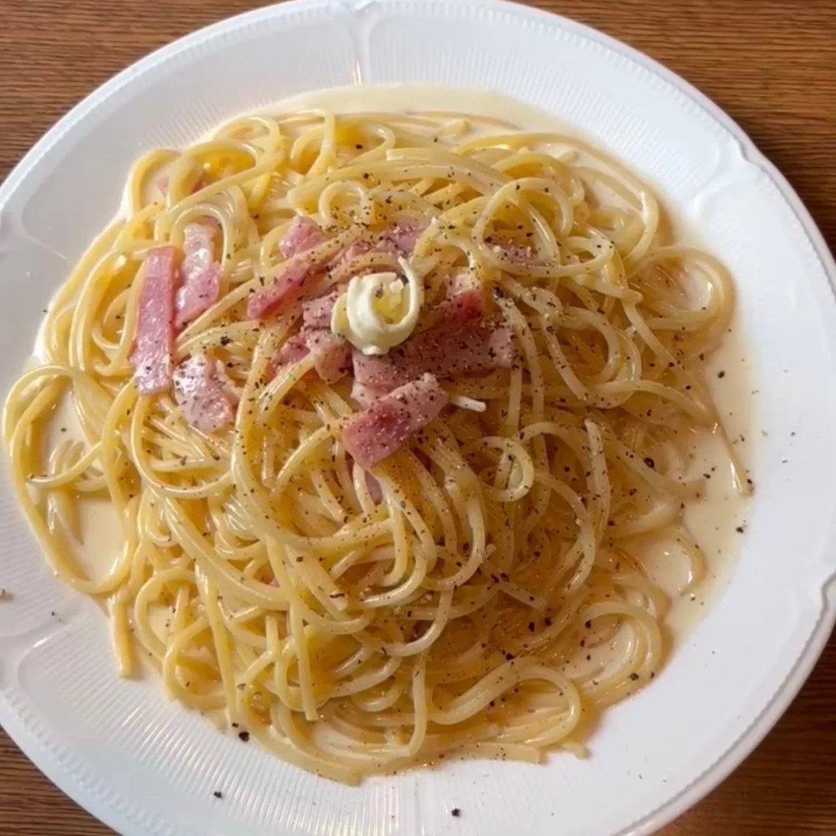 白い皿に盛られたクリーミーなソースのスパゲッティ、カルボナーラ