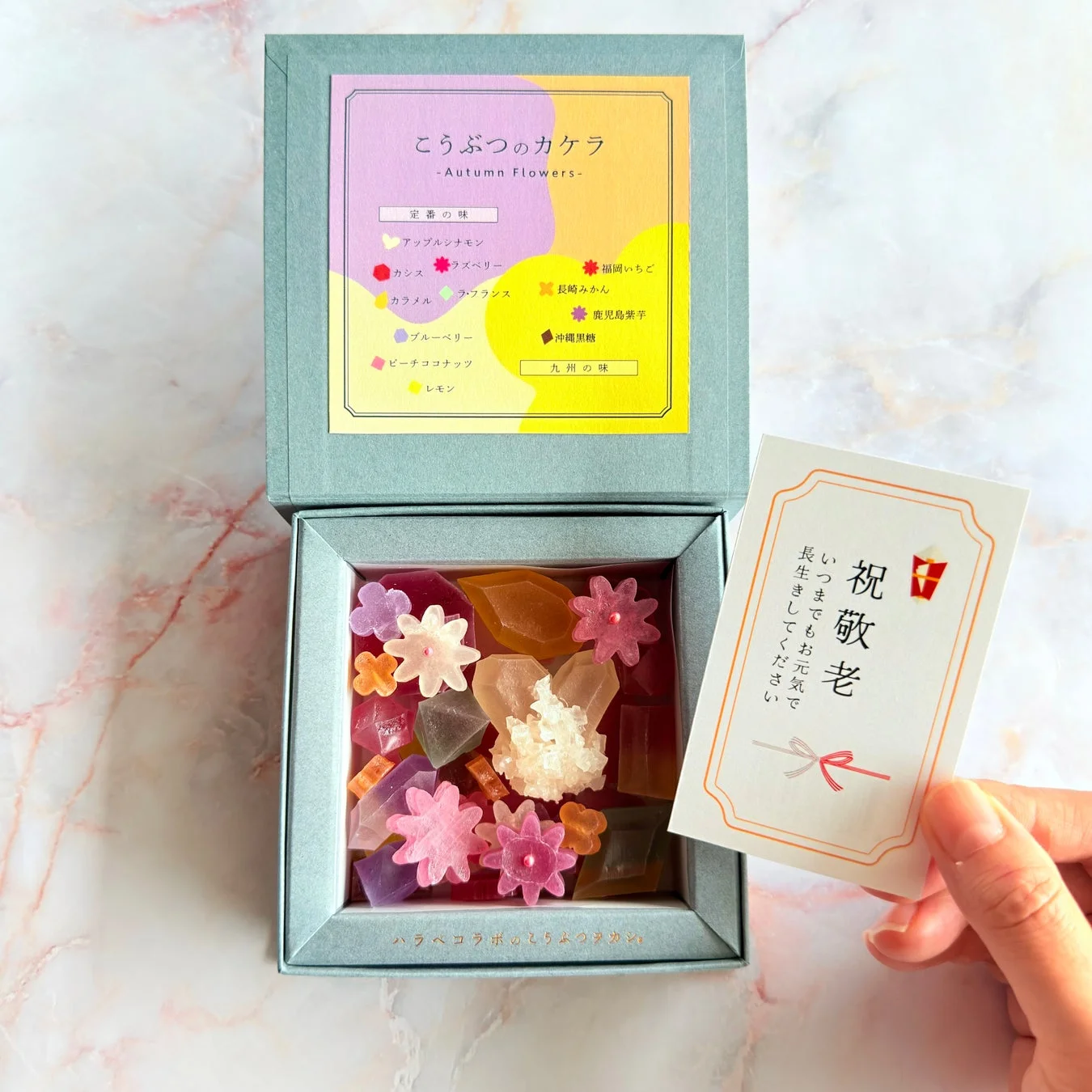 色とりどりの琥珀糖や花形のお菓子が詰められたギフトボックスと「祝 敬老」のメッセージカード